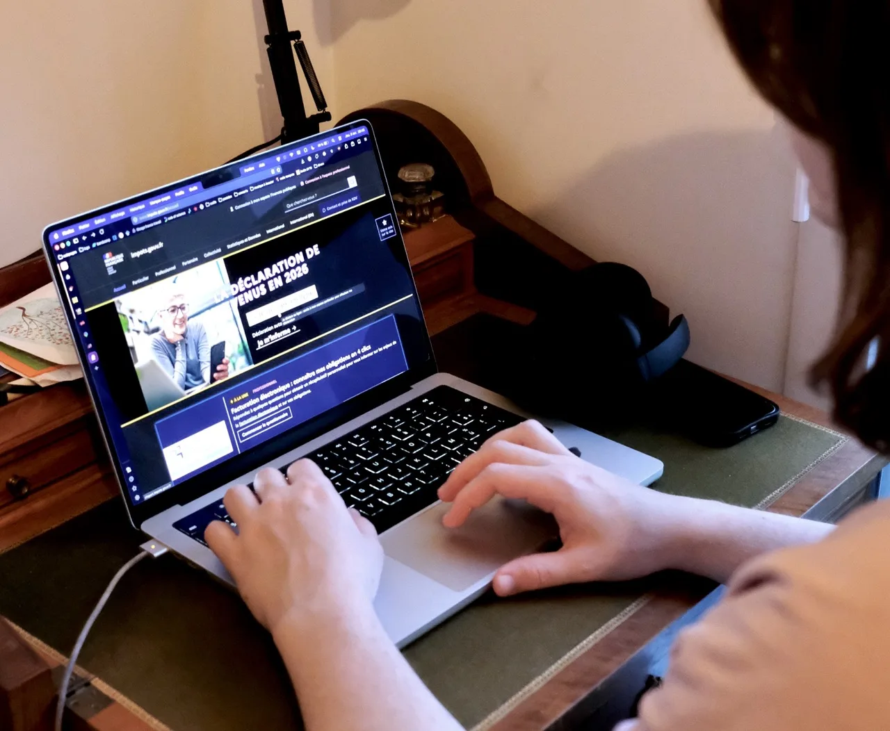 Une personne de dos rempli sa déclaration d'impot en ligne